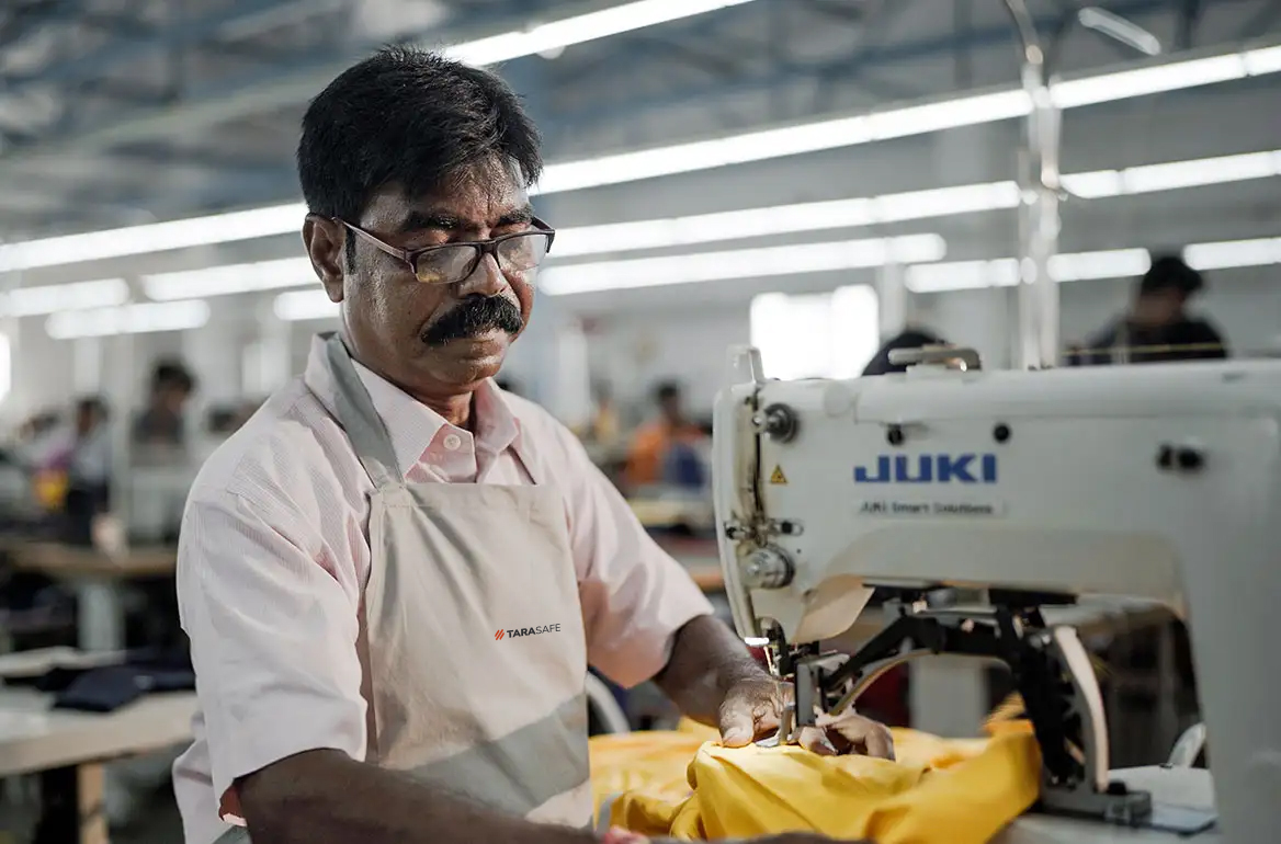 Worker sewing flame-resistant clothing at Tarasafe manufacturing unit